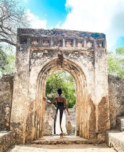 A traveler standing in a stone archway doorway among the Gede Ruins